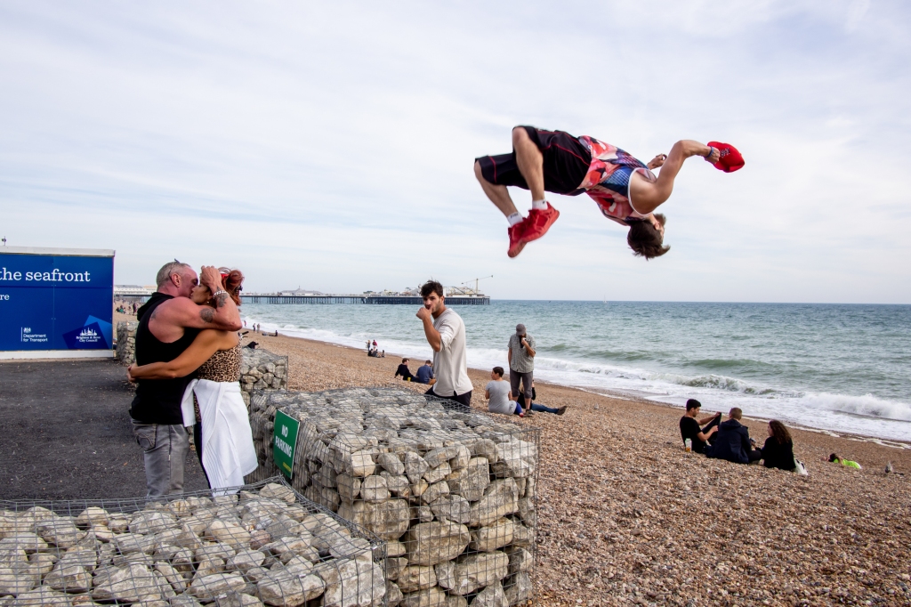 Street photography of a couple kissing and leaping man, in Brighton.